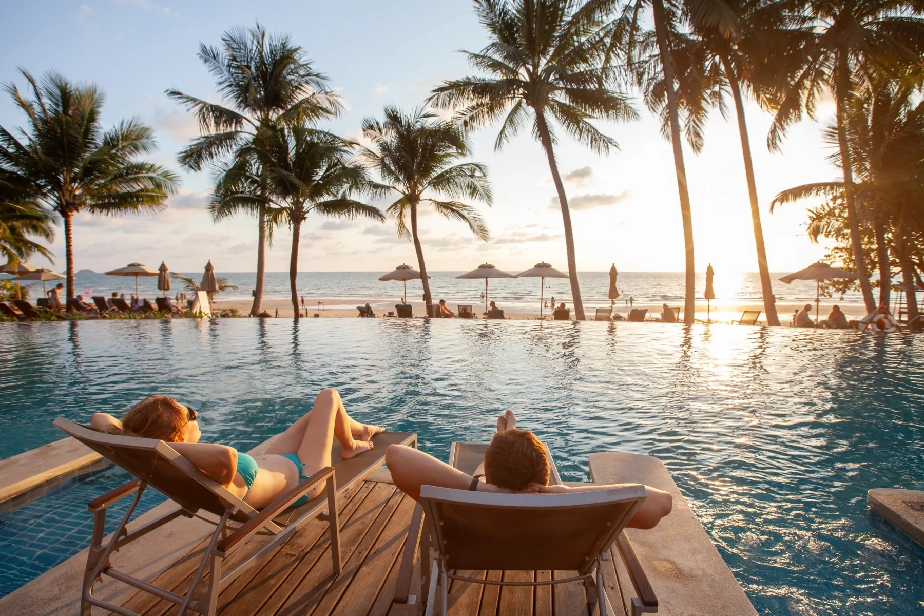 Palms and loungers around the pool as the sun drops