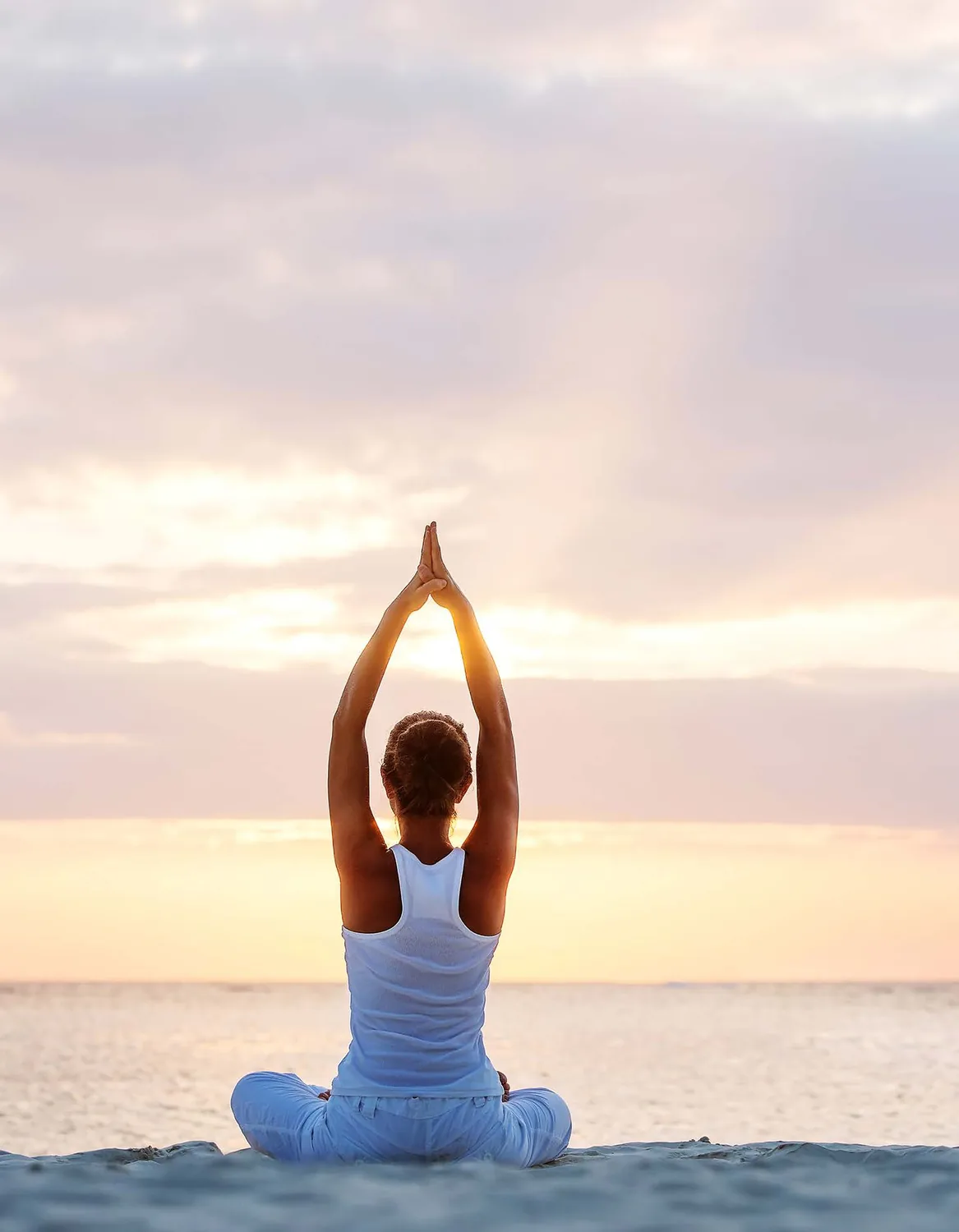 A figure at yoga against a sunset over the sea